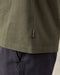 Closeup of 'Outerknown' tag on seem of olive green t-shirt