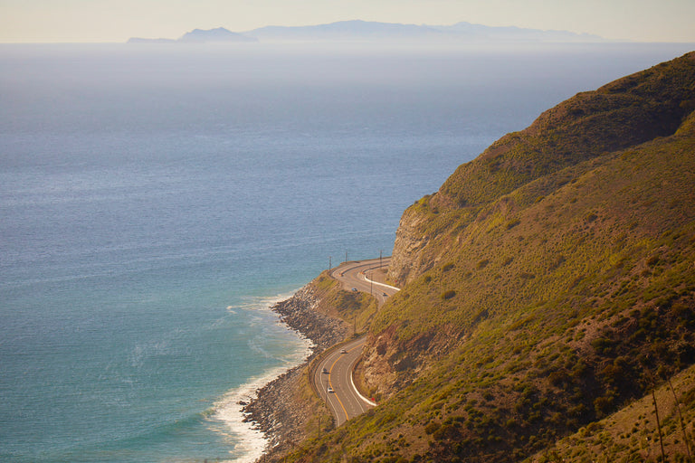 landscape view of a mountain side that connects to the ocean with a rod in the middle.