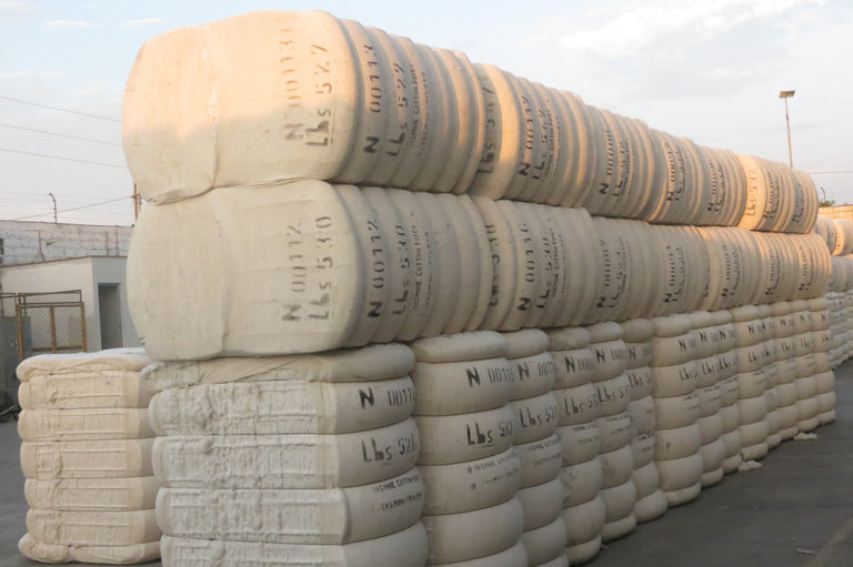 bails of cotton stacked in a factory yard.