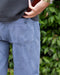 Person wearing blue pants with a green leafy background