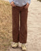 Person wearing brown corduroy pants standing on a dirt path.