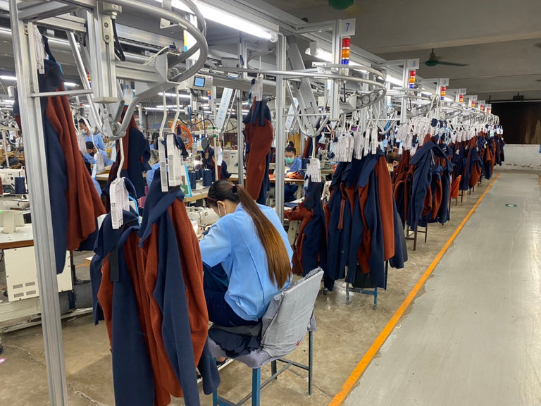 Interior of factory with sewing machines and pieces of fabric.
